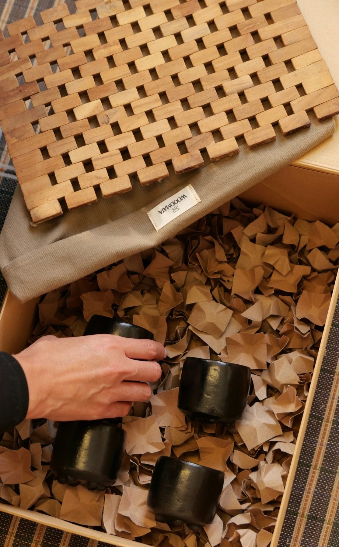Détail des quatre tasses OIA en terracotta noire dans le coffret Woodmata, avec le dessous de plat.