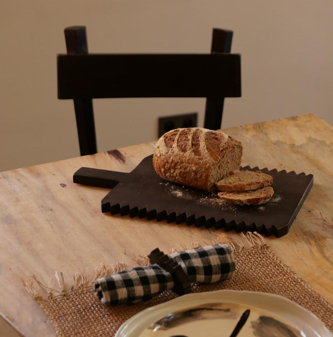Planche à découper PIKO avec du pain sur une table dressée.